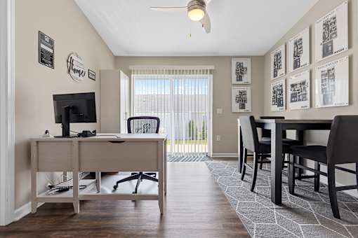 A room with a desk, chairs, and pictures on the wall.