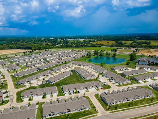 A bird's eye view of a residential area with houses, roads, and a lake.