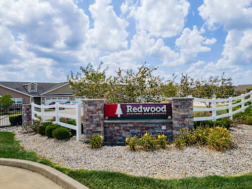 A sign that says Redwood in front of a white fence.