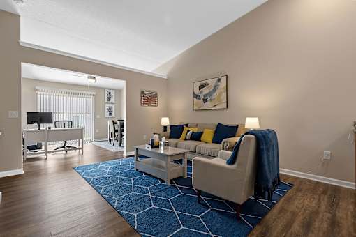 A living room with a blue rug and a white couch.