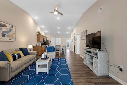 A living room with a blue carpet and a ceiling fan.