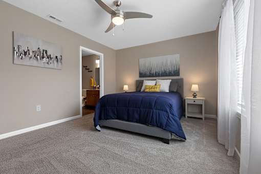 A bedroom with a bed, nightstand, and a painting on the wall.