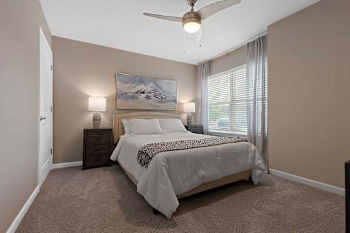 A bedroom with a bed, a ceiling fan, and a painting on the wall.