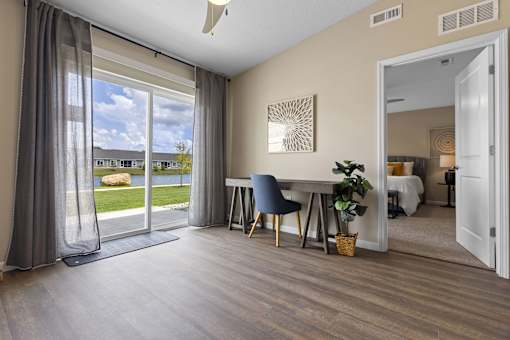 A room with a sliding glass door leading to a patio, a dining table with chairs, and a mirror on the wall.