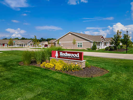 A Redwood sign is in front of a building with a green lawn.