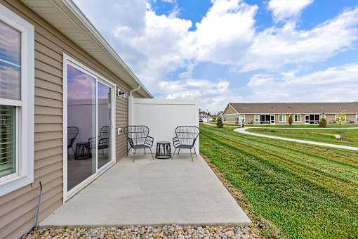 A patio with a table and chairs is in front of a house.