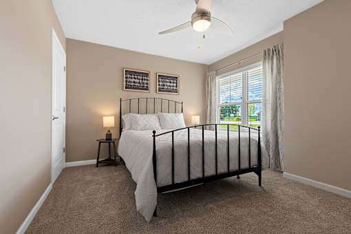A bedroom with a bed, nightstand, and window.