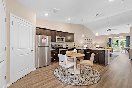 A modern kitchen with a dining table and chairs in the middle.