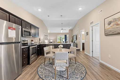 A kitchen with a dining table and chairs in the middle of the room.
