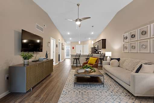 A living room with a white couch, a coffee table, and a television.