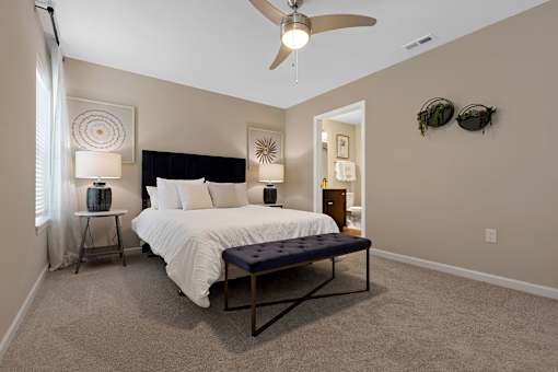 A bedroom with a large bed and a ceiling fan.