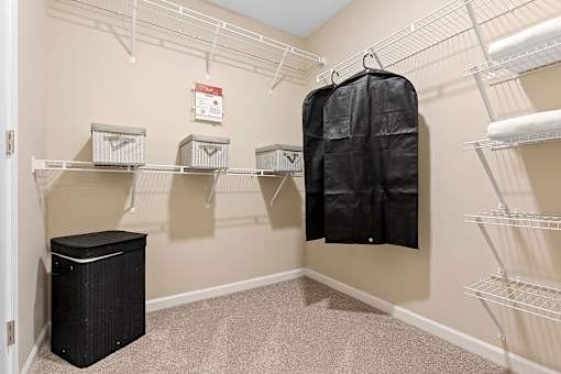 A walk-in closet with a hanging bag and shelves.