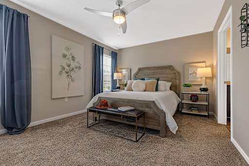 A bedroom with a bed, nightstands, and a ceiling fan.
