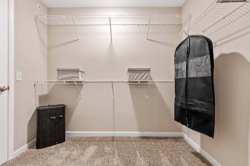 A walk-in closet with a black coat hanging on a hanger.