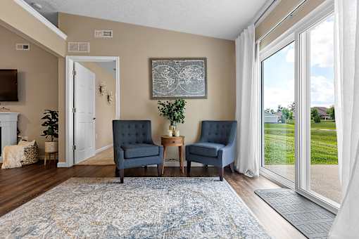 A living room with a blue rug and two chairs.