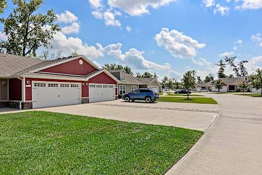 A blue car is parked in front of a red garage.