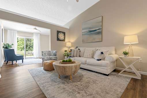 A living room with a white couch, a wooden coffee table, and a painting on the wall.