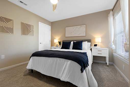 A bedroom with a white bed and a white nightstand.