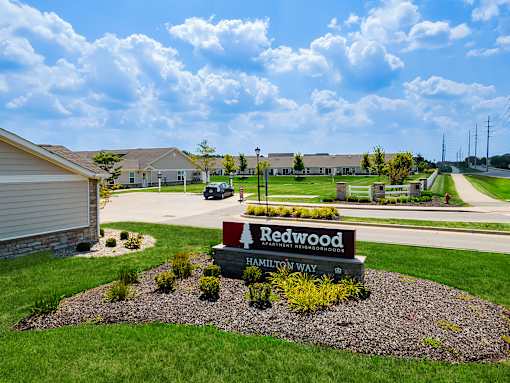 A sign for Redwood Estates is in the foreground of a grassy area.