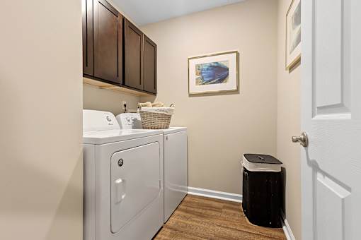 A laundry room with a washer and dryer and a basket of clothes.