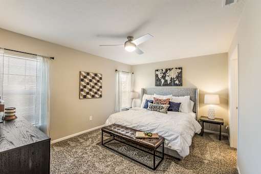 A bedroom with a bed, a ceiling fan, and a window with blinds.