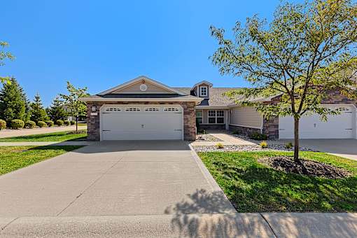 A house with a driveway and a tree in front.