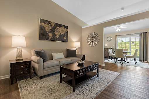A living room with a beige couch, a coffee table, and a large painting on the wall.