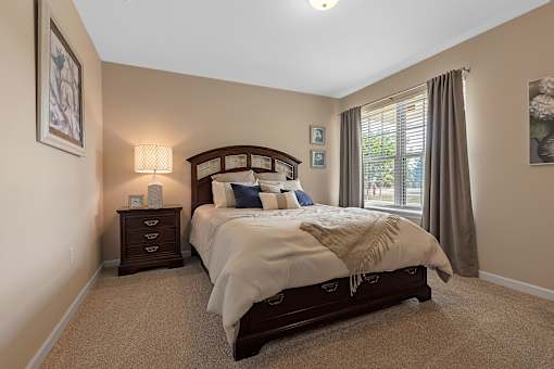 A bedroom with a large bed and a window with curtains.