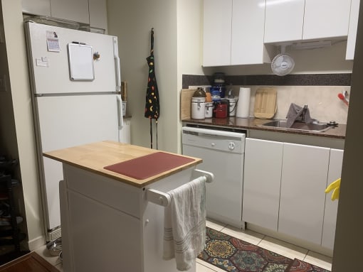 a small kitchen with white cabinets and a white refrigerator