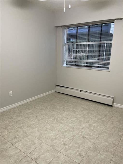 an empty room with a window and a tiled floor