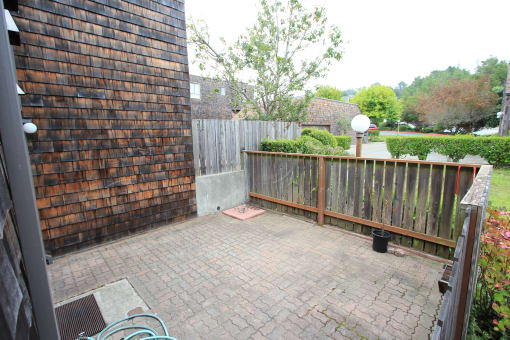 a patio with a wooden fence and a brick wall