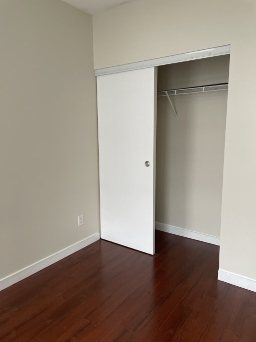 an empty bedroom with a closet and a wooden floor