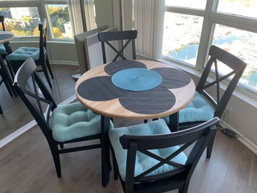 a dining room with a round table with blue chairs and a window