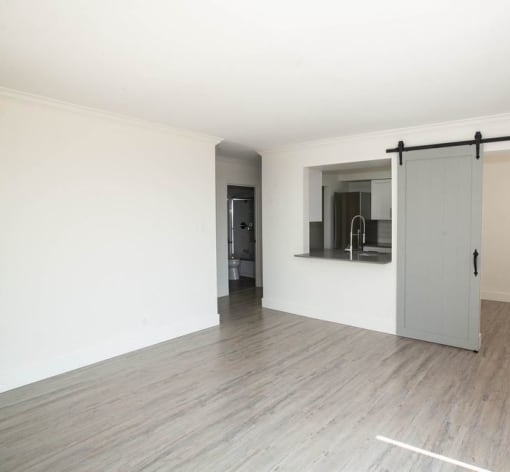 an empty living room with a sliding door to the kitchen