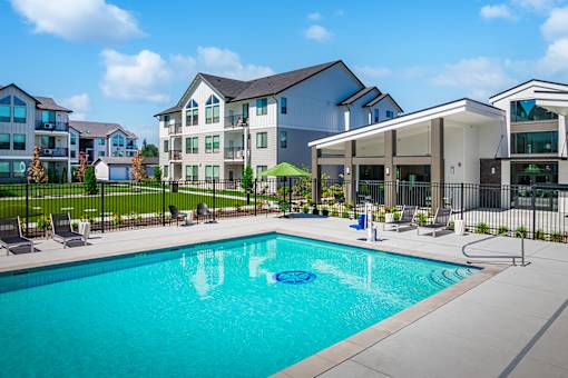 A swimming pool in front of a building with a black fence around it.