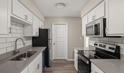 an empty kitchen with white cabinets and black appliances