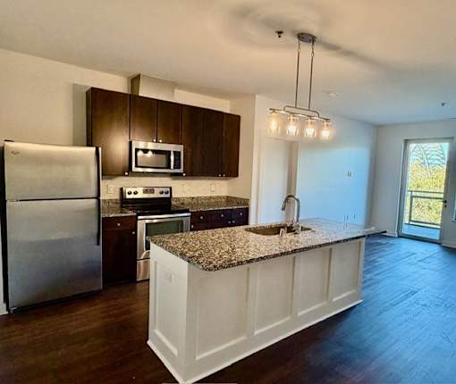 A kitchen with a granite countertop and stainless steel appliances.