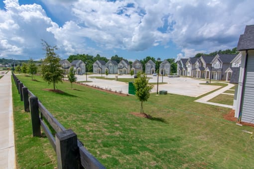 a grassy area with trees in front of a row of houses