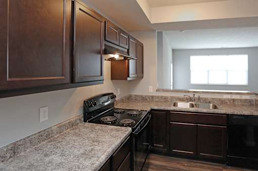 A kitchen with dark wood cabinets and a granite countertop.