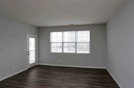 A room with a large window and wooden floors.
