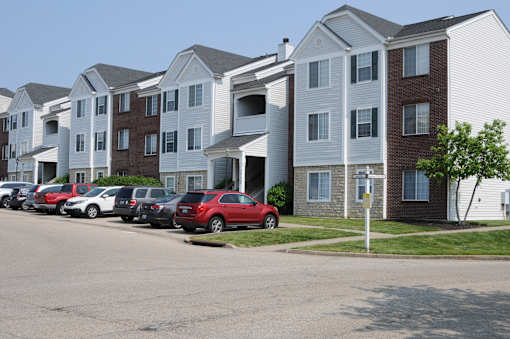A red car is parked in front of a white building.