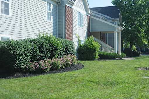 A house with a well-kept lawn and a flower bed in front.