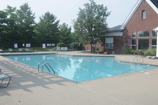 A swimming pool with a diving board and a building in the background.