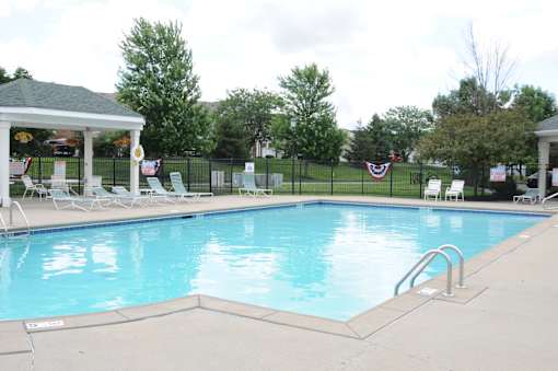 A pool with a gazebo and chairs around it at The Legends at Steeplechase Apartments, Richwood, KY