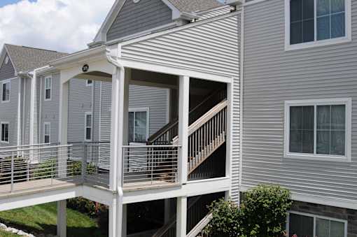A white house with a balcony and stairs leading to the second floor.
