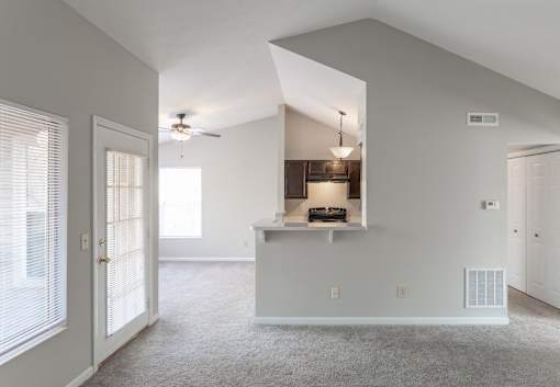 A spacious living room with a kitchenette and a ceiling fan.