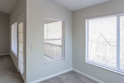 A room with two windows covered in white blinds.