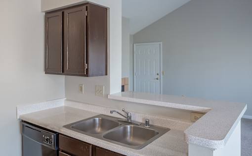 A kitchen with a white counter top and brown cabinets.