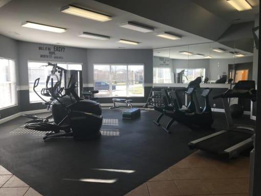 A gym with a variety of equipment including treadmills, weights, and exercise machines at The Legends at Steeplechase Apartments, Richwood, KY, 41094
