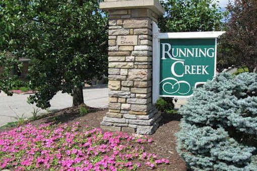 A stone pillar with a sign that says Running Creek.
